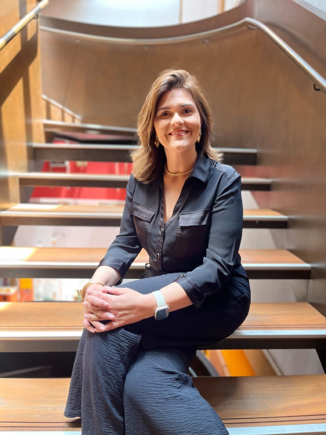 Luana Claudino sentada em uma escada, sorrindo